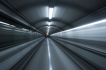 Blurry abstract motion perspective from inside a fast-moving subway train or vehicle traveling through a dimly lit tunnel with streaks of light illuminating the path forward