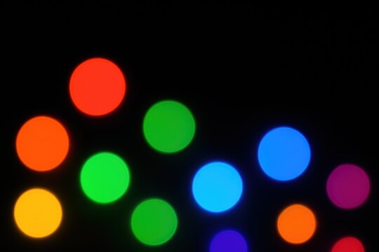 Rainbow bokeh defocused lights on dark backdrop festive disco party background