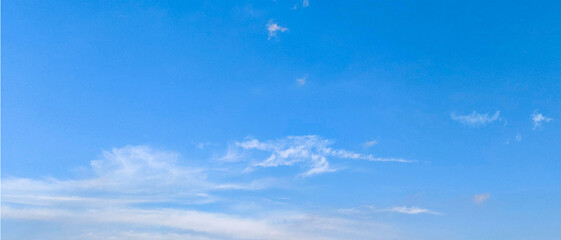 Blue Sky and Wispy Clouds. A serene view of a bright blue sky adorned with wispy, delicate white clouds. 