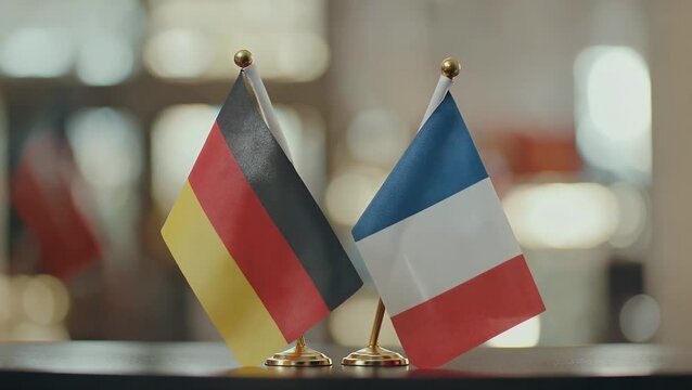 Two national banners from European nations placed together on work surface against soft blur
