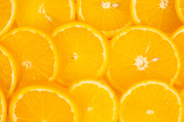 Many thin orange slices are arranged edge to edge creating a full background texture of citrus.