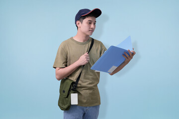 A casual young man in a cap holds blue folders, standing in profile with a green bag. Perfect for education, student life, and everyday youth lifestyle visuals