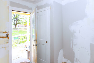 Room in middle of renovation with an open door revealing sunny outdoor space tools