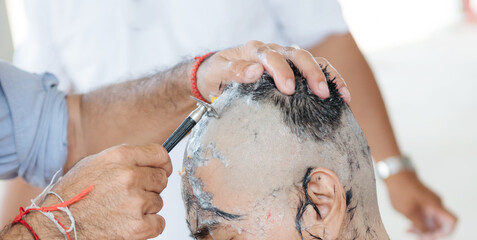 Close-up of a man having his head shaved clean with a straight razor, foam and hair remnants visible on scalp.
