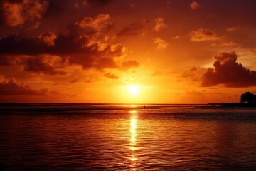 Fototapeta premium A vibrant orange sunset reflects over calm ocean waters with scattered clouds and a silhouette of trees on the horizon