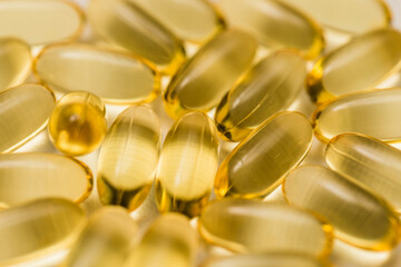 Closeup of many yellow clear fish oil omega-3 capsules on white background 