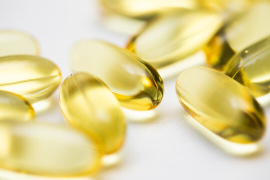 Closeup of clear yellow fish oil omega gel capsules medicine on white background 