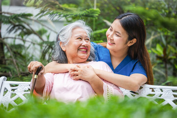 Senior woman with a walking stick enjoys time with her caregiver, Happy caregiver and elderly woman laughing in the garden, Young nurse assisting an older lady in her backyard