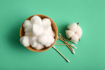 Bowl with cotton balls, swabs and flower on turquoise background