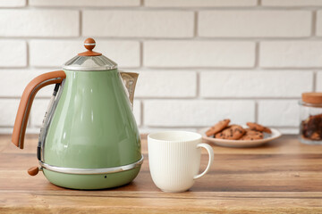 Modern green electric kettle and cup on counter in kitchen