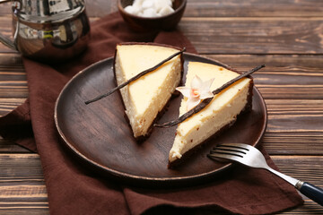 Plate with pieces of sweet vanilla cheesecake on wooden background