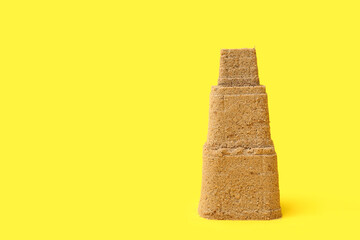 Beautiful sand castle on yellow background
