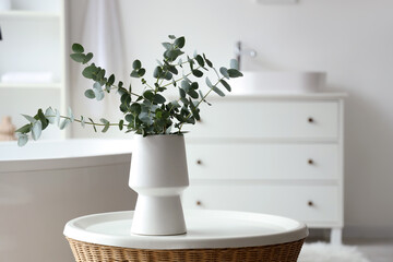 Vase with eucalyptus twigs on table in interior of bathroom