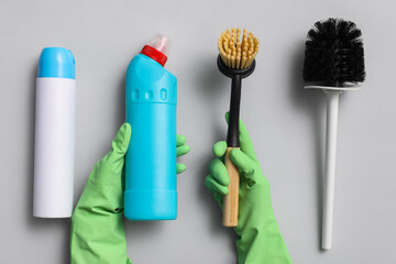 Hands of janitor and cleaning supplies on light background