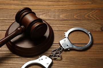 Obraz premium Handcuffs with judge's gavel on wooden background, closeup