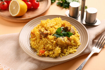 Plate of tasty pilaf with parsley and lemon on orange background, closeup