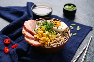 Bowl of ramen noodle soup with meat and canned corn seeds on dark background, closeup