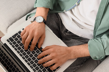 Man with wristwatch using laptop at home, closeup
