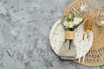 Stylish table setting with golden cutlery and beautiful flowers on grunge background
