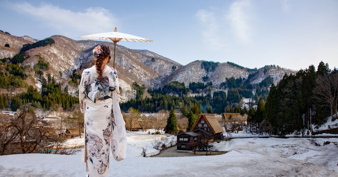 Japanese woman holding an umbrella and wearing a traditional japanese kimono - The Historic Villages of Shirakawa with suspension bridge in winter - Japan