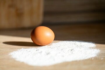 Egg and flour on a sunlit table, ready for cooking. Simple ingredients for baking