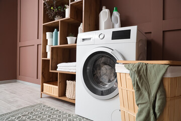 Interior of laundry room with washing machine, basket and shelf unit
