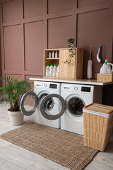 Interior of laundry room with washing machines, basket and plants