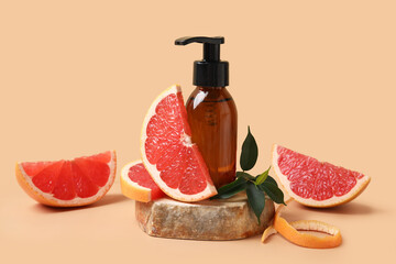 Bottle of cosmetic product, pieces of grapefruit and stone on beige background, closeup