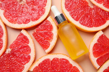 Bottle of cosmetic product and slices of grapefruit on beige background, closeup
