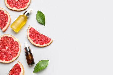 Composition with bottles of cosmetic products, green leaves and slices of grapefruit on white background, closeup