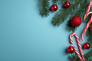 Christmas background with candy canes fir branches red ornaments on blue flat backdrop, top view copy space festive minimalist design for card social media