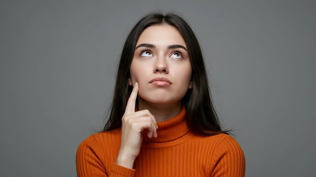 Young woman thinking with finger on chin, looking up