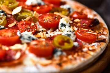 Pizza with salami, jalapeno pepper, cherry tomatoes and mozzarella cheese. Soft focus.	