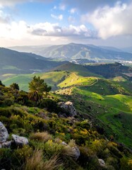 Verdant hillsides roll into the distance under a partly cloudy sky