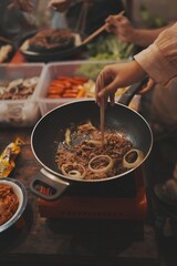 A person stir-frying meat with onions.