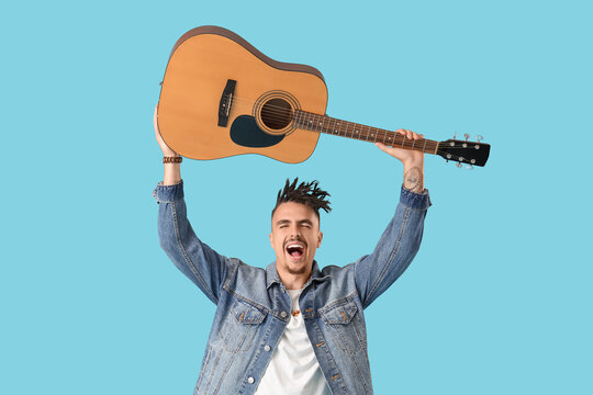 Young man with dreadlocks and guitar on blue background - Powered by Adobe