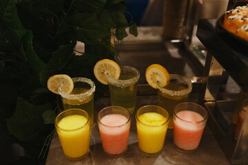 Various colorful drinks with lemon slices on display.