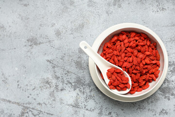 Bowl with dried goji berries on grey grunge background, closeup