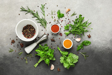 Composition with herbs, mortar, pestle and bowls with spices on grey grunge background
