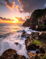 Vibrant sunset over a rocky coastline, waves washing over the rocks