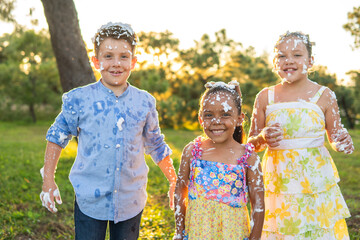 3 niños felices y sonrientes amigos hermanos bañados en espuma artificial al aire libre en un...