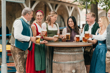 Friends men and women toast with large beer mugs in Bavarian beer garden enjoying German culture leisure friendship and festive celebration