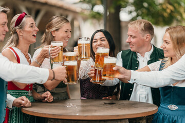 Joyful group of friends in Bavarian beer garden toast with mugs of beer enjoying friendship leisure culture Oktoberfest and festive tradition