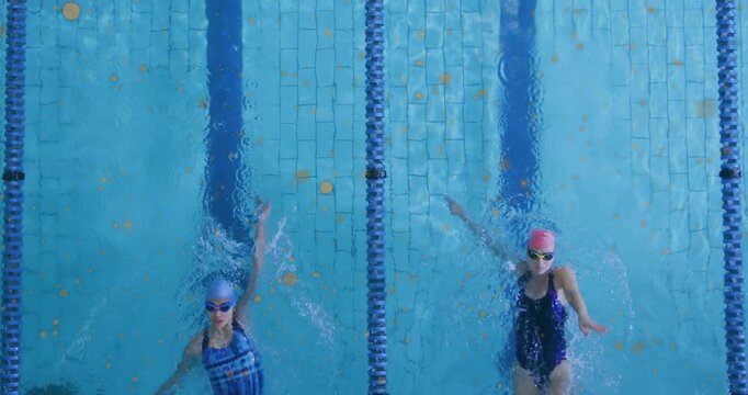 Two female swimmers pushing off pool wall and performing backstroke drills in sync with swim caps