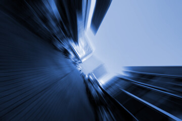 Abstract motion blur background of modern city buildings with a dynamic zoom effect, creating a futuristic urban perspective in blue tone.
