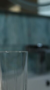 Worn, blue toothbrush sits in a clear glass in a bathroom setting. Time to switch out that toothbrush. This is for good oral and dental hygiene.