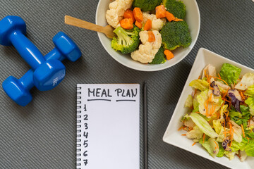 Calorie control and diet meal plan with healthy eating lifestyle, salad, vegetables, dumbbells and yoga mat, concept of balance, fitness and nutrition planning.