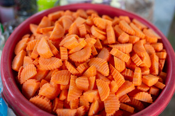A large number of chopped carrots in a red container