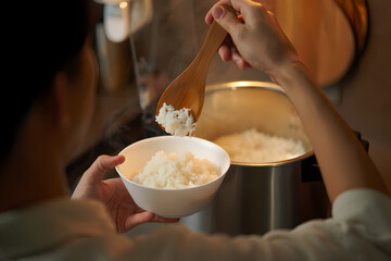 Fototapeta premium Serving Steaming Cooked Rice from Pot into a White Bowl