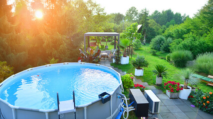 Garden of a suburban house in summer in which you can see a removable swimming pool, pergola in a...